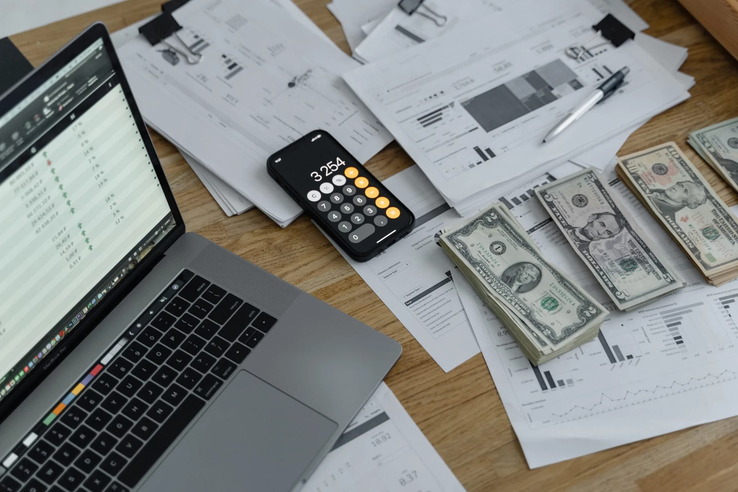 Image d'un bureau avec un ordinateur, des billets et un téléphone sur l'application calculatrice