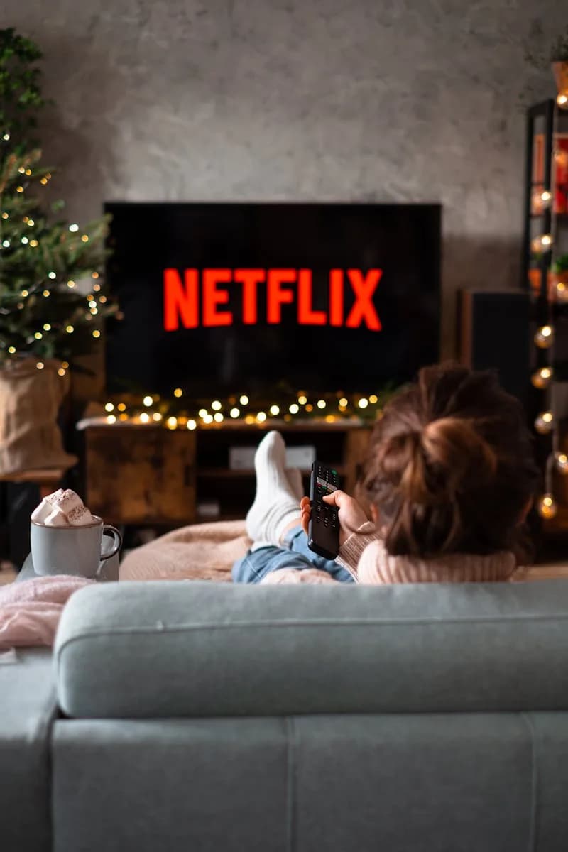 Back View of a Woman Sitting on a Sofa and Watching Television during christmas / noël