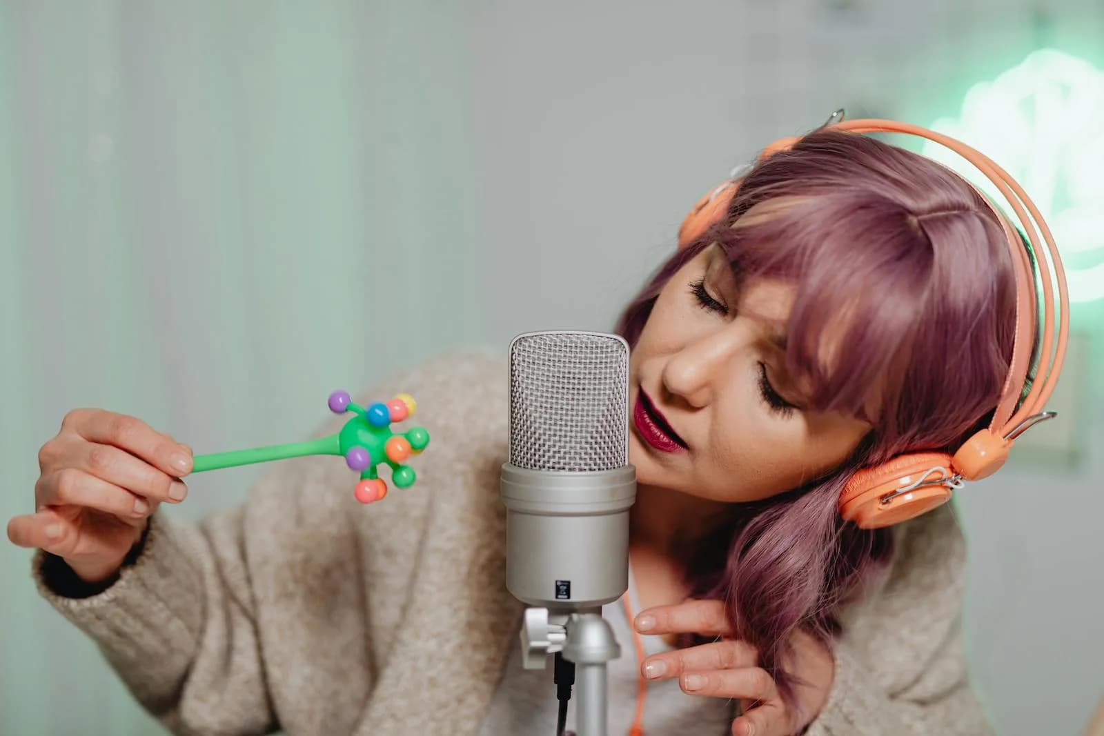 Woman with purple hair using a microphone for ASMR video creation.