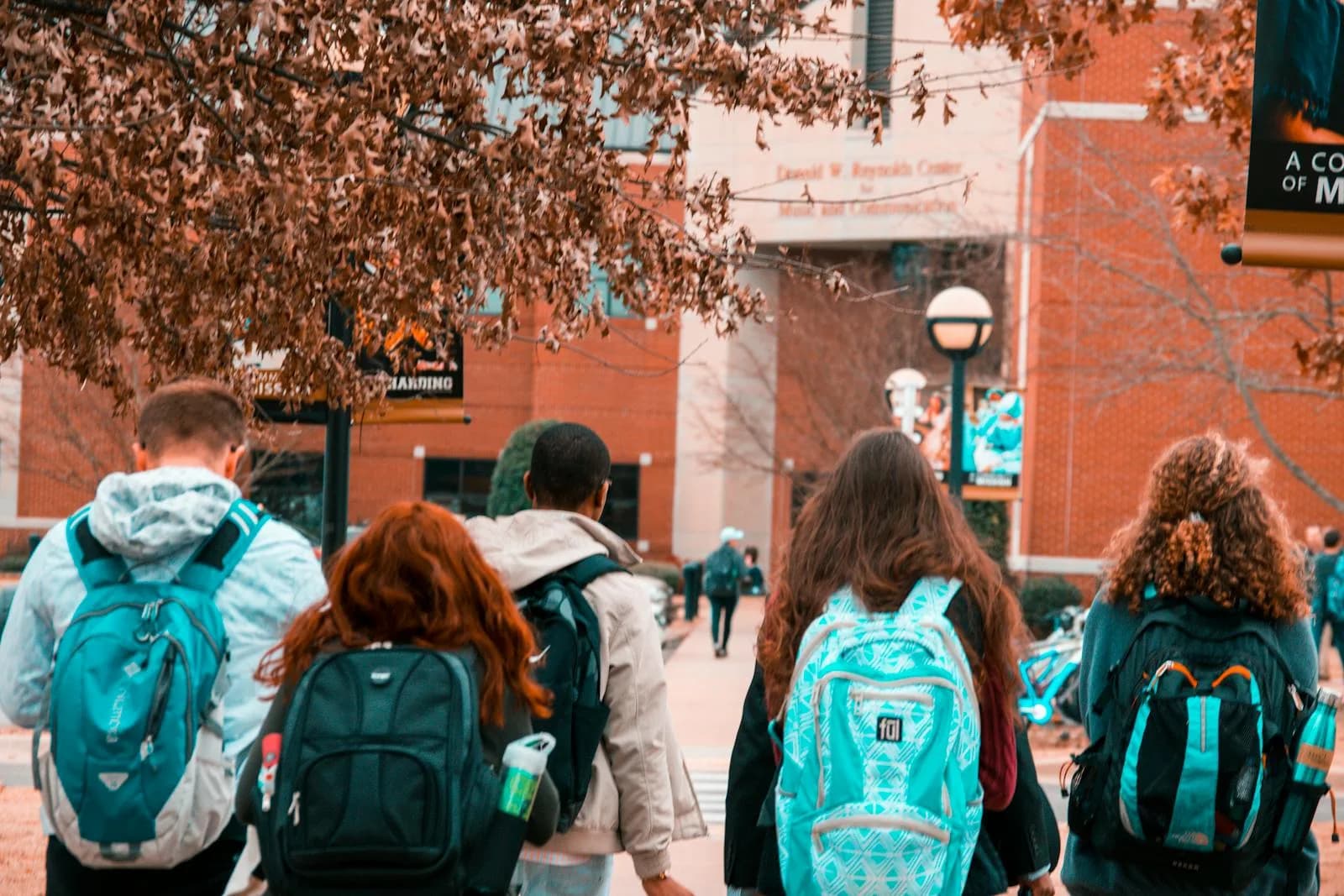 Un groupe d'étudiants avec des sacs à dos marchant ensemble à l'extérieur sur le campus. Admission universitaire, rentrée
