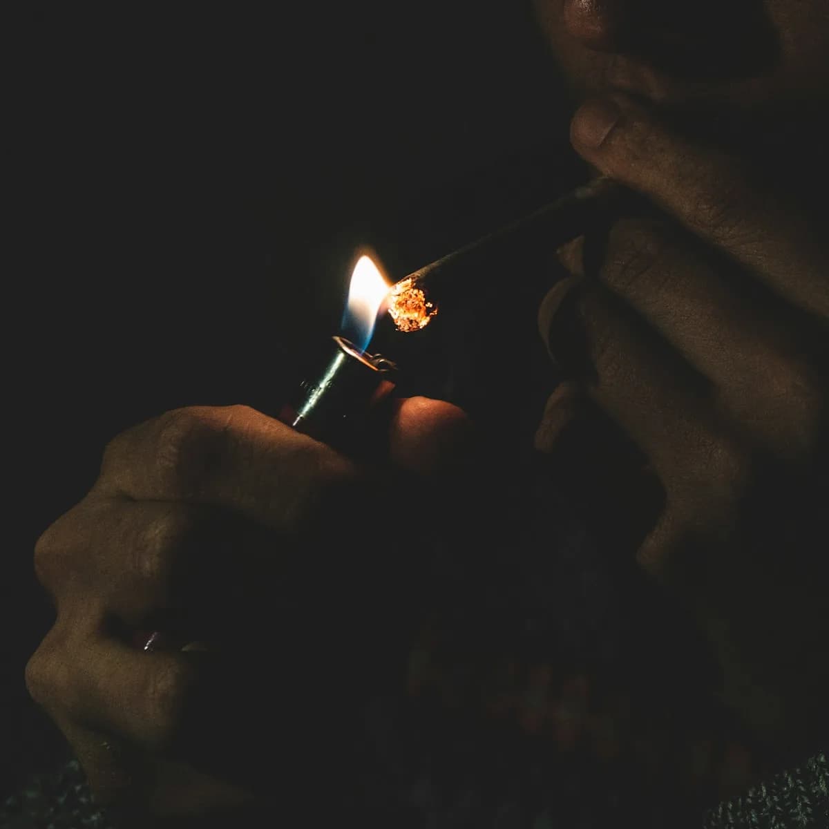 Une personne allume un joint de cannabis