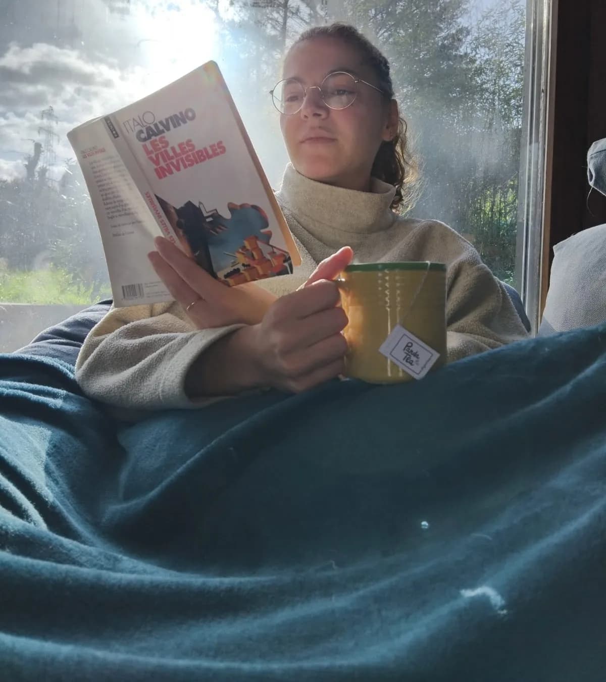 Une jeune femme lit les Villes invisibles sous une couverture