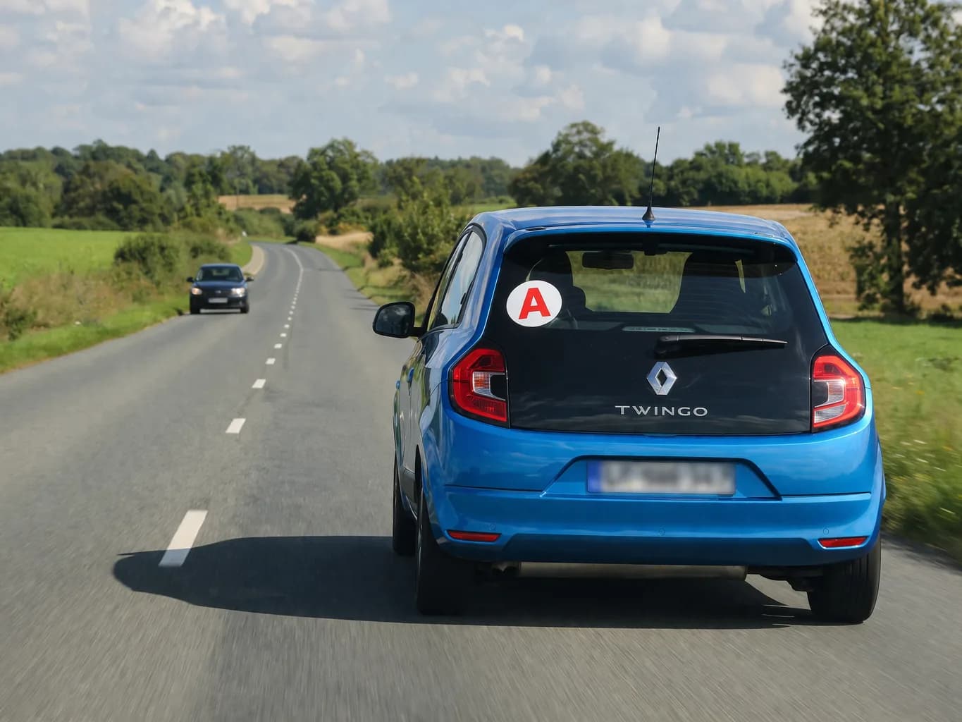 voiture jeune permis avec un A sur la route, vue de dos, avec une voiture qui arrive en face