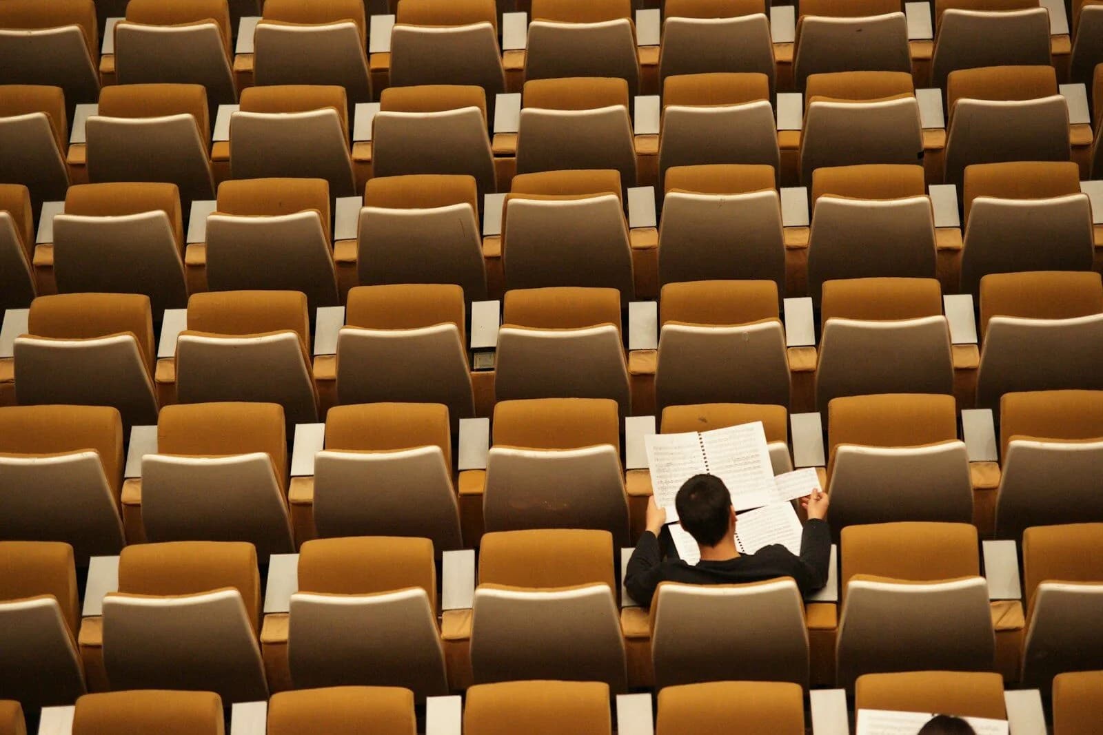 person reading alone in empty lecture hall