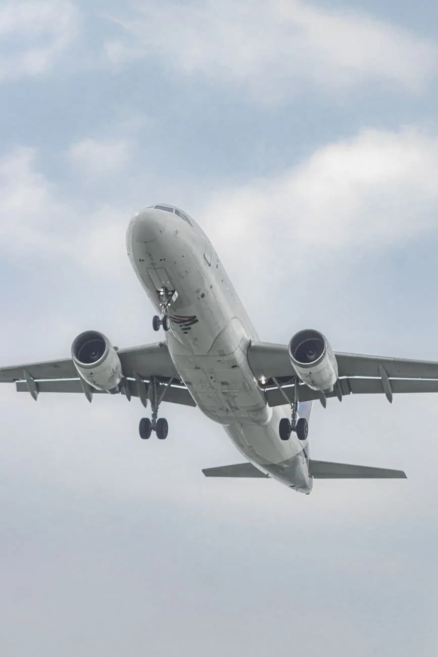 Un avion de ligne capturé en plein vol contre un ciel nuageux, illustrant l'aviation moderne.